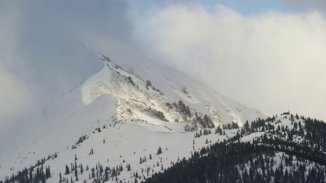 一个被照亮的雪峰在洛基山脉附近的弗里斯科，科罗拉多州在暴风雪云下的冬天视频素材