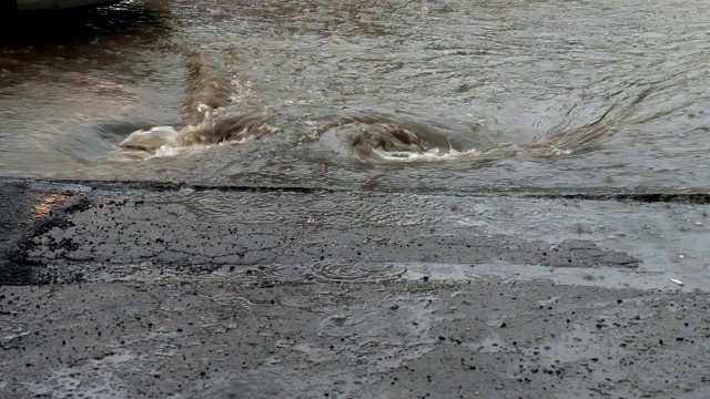 被洪水淹没的城市街道上的水流入暴雨排水沟。视频素材