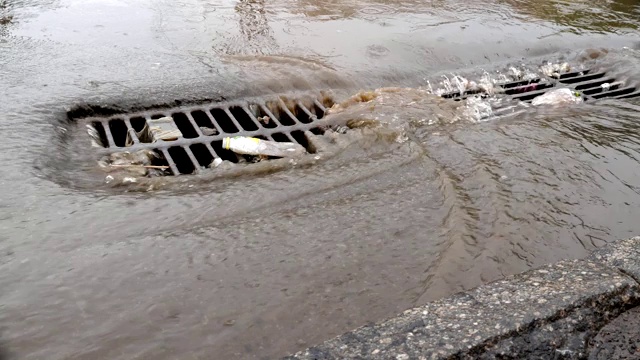 一个城市的暴雨，淹没了街道和下水道的井盖。视频素材