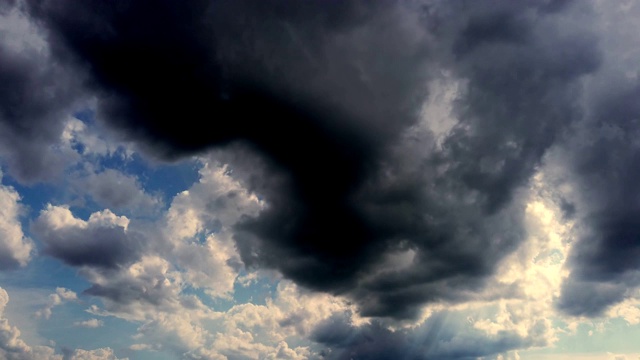 时光流逝，深蓝的天空，运行灰色的雷云，雨云。罕见的太阳光穿过云层视频素材