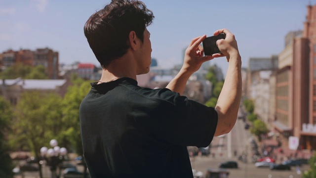 后视图，一个不认识的人旅游拍摄城市的智能手机视频素材