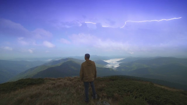 那个在闪电背景下走在山上的人视频素材