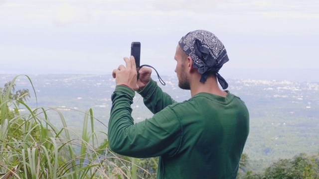 旅人站在山顶上用手机拍摄全景照片。一名游客用智能手机拍摄高山美景。视频素材