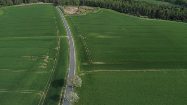 鸟瞰图乡村道路与交通通过景观与农业领域，春天。法兰克尼亚,巴伐利亚,德国。视频素材