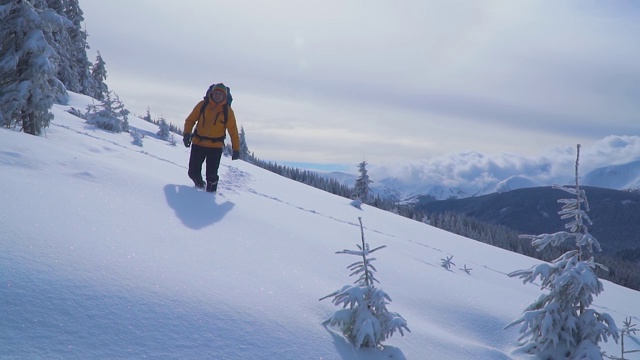 一位游客在山中的雪中行走。视频素材