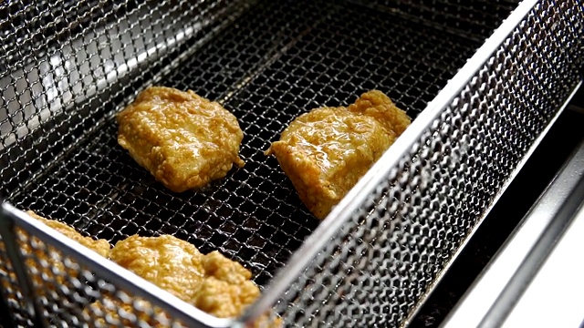 烹饪油炸面包屑鸡。在热油炸锅里炸鸡块的特写视频素材