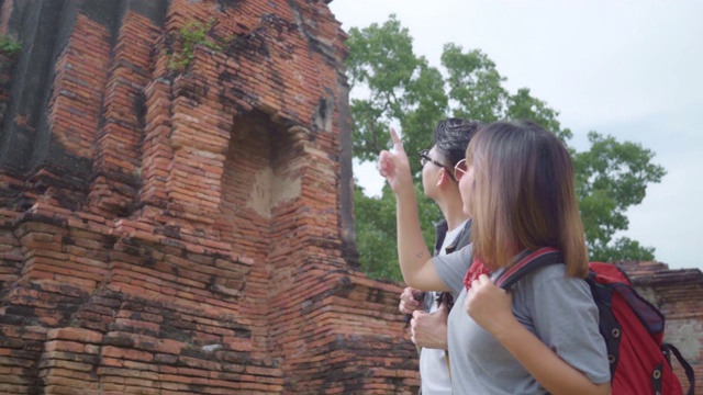 旅行者亚洲夫妇在泰国大城府度假，背包客甜蜜的夫妇享受他们的旅程在传统城市惊人的地标。生活方式情侣旅游度假概念。视频素材