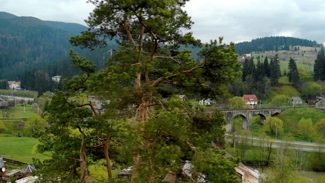 一座古老的石质铁路桥横跨湍急的河流和山间的公路在一个小村庄视频素材