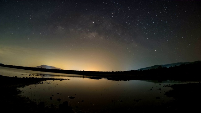 时间流逝的鱼眼:夜晚，天上的星星反射光线。银河之上的山脉和池塘湄普拉昌大坝和水库，碧府，泰国视频素材