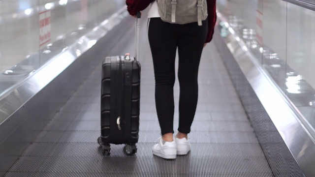 旅行家女士走过机场航站楼与手提箱在机场，旅游概念视频素材