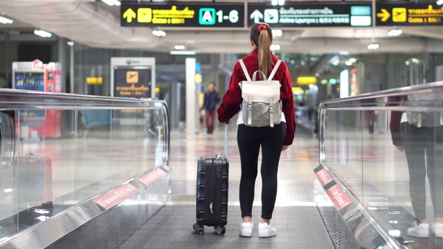 旅行家女士走过机场航站楼与手提箱在机场，旅游概念视频素材