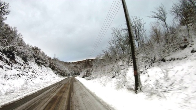 来自挡风玻璃的冬季道路POV。伟大的镜头，一个泥泞的冬天的道路被雪包围，从汽车的前面看道路移动的观点拍摄视频素材