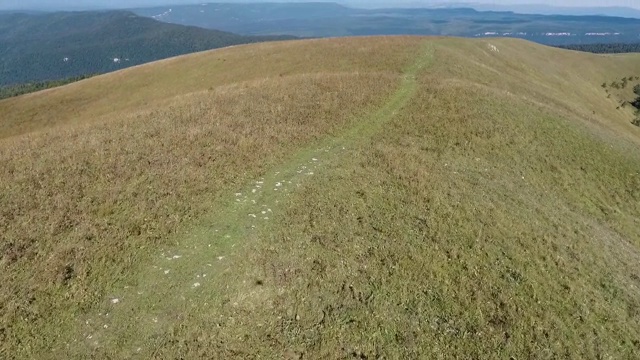 在山区的一个小山上飞过一条土路。视频素材