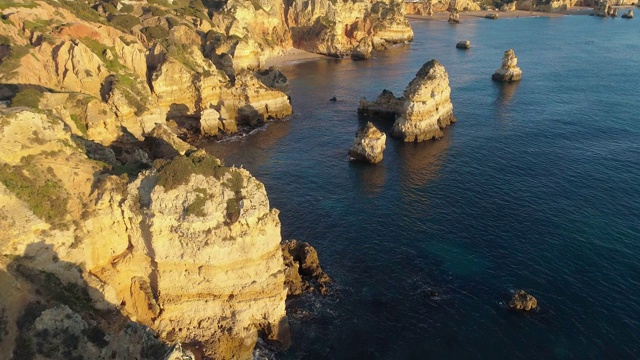 阿尔加维,葡萄牙。在日出时飞过大西洋碧绿的海水和海岸上的黄色岩石。空中射击,4 k视频素材