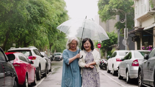 两个老年妇女在一个下雨天在城里散步视频素材