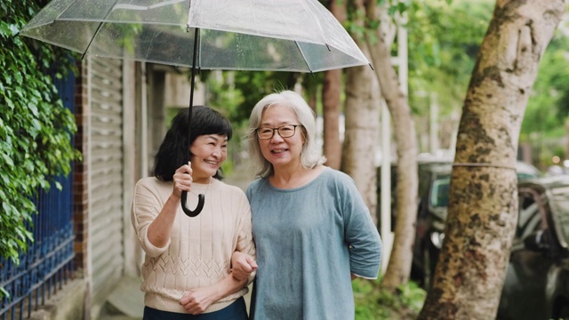 两个老年妇女在一个下雨天在城里散步视频素材