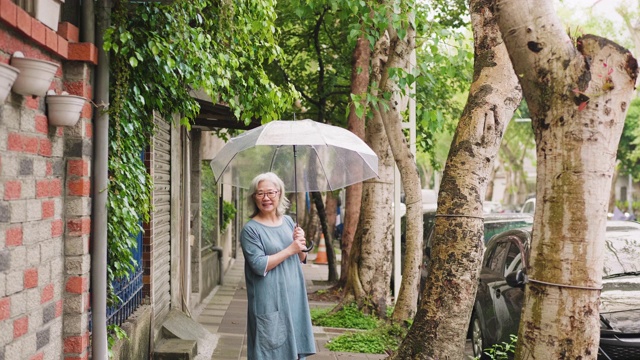 一个快乐的老女人带着伞在一个雨天的城市视频素材