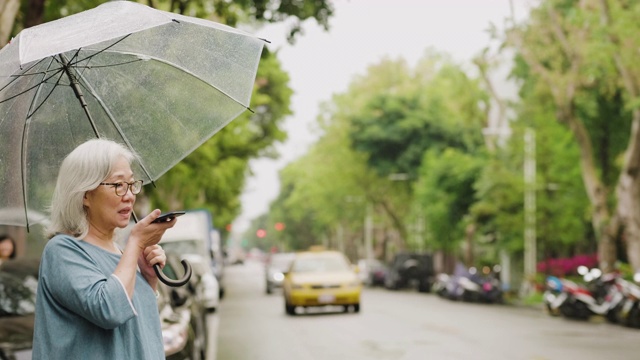 一个雨天，一位老妇人在城市里等出租车视频素材