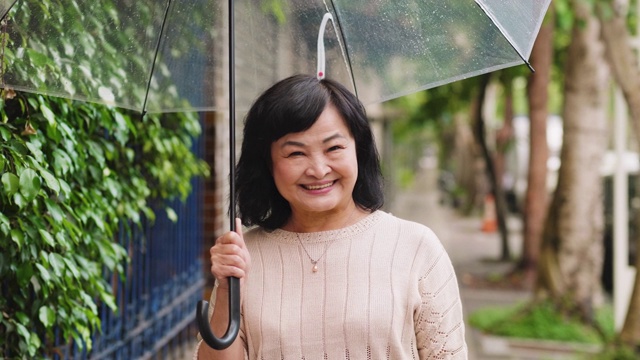 一个快乐的老女人带着伞在一个雨天的城市视频素材