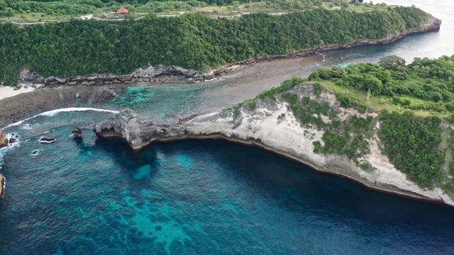 鸟瞰图的绿色热带海岸努沙佩尼达岛，阿图海滩，巴厘岛，印度尼西亚。清澈的蓝色海浪翻滚到海滩。4 k视频素材