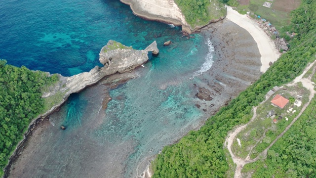 鸟瞰图的绿色热带海岸努沙佩尼达岛，阿图海滩，巴厘岛，印度尼西亚。清澈的蓝色海浪翻滚到海滩。4 k视频素材