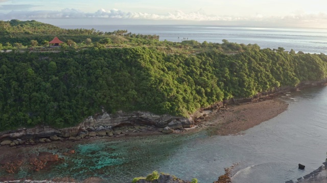 鸟瞰图的绿色热带海岸努沙佩尼达岛，阿图海滩，巴厘岛，印度尼西亚。清澈的蓝色海浪翻滚到海滩。4 k视频素材