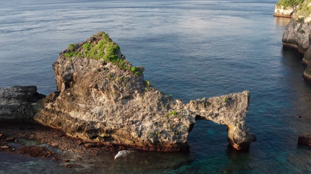 鸟瞰图的绿色热带海岸努沙佩尼达岛，阿图海滩，巴厘岛，印度尼西亚。清澈的蓝色海浪翻滚到海滩。4 k视频素材