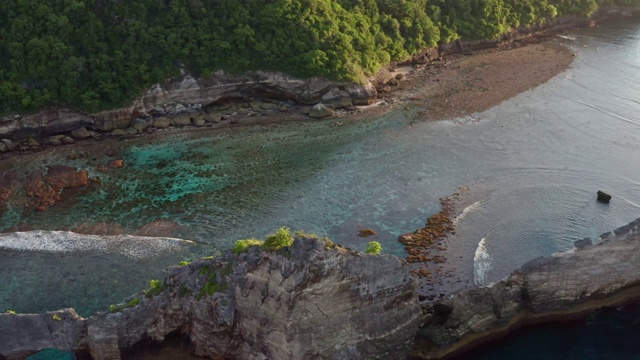 鸟瞰图的绿色热带海岸努沙佩尼达岛，阿图海滩，巴厘岛，印度尼西亚。清澈的蓝色海浪翻滚到海滩。4 k视频素材