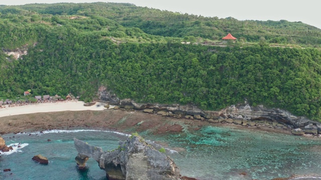 鸟瞰图的绿色热带海岸努沙佩尼达岛，阿图海滩，巴厘岛，印度尼西亚。清澈的蓝色海浪翻滚到海滩。4 k视频素材