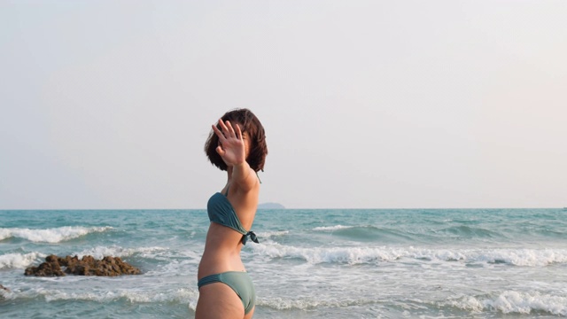 亚洲性感的女人走在海滩上的夏天与快乐的情感。亚洲女人穿着比基尼在海边热带旅游假期。4K分辨率和慢镜头。视频素材