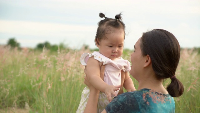 日落时分，年轻的母亲和女儿在草地上。手持拍摄的视频素材