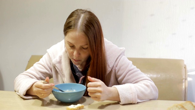 穿着浴袍的生活方式女人在厨房的餐桌上喝着鸡汤视频素材