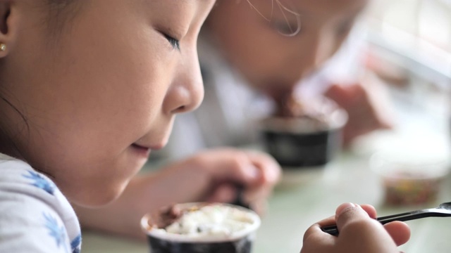 亚洲小孩坐在咖啡馆和家人吃冰淇淋，生活方式的概念。视频素材