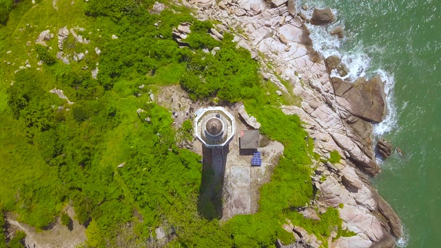 顶视图海灯塔在岩石岛在蓝色的海。海洋绿岸空中景观灯塔视频素材