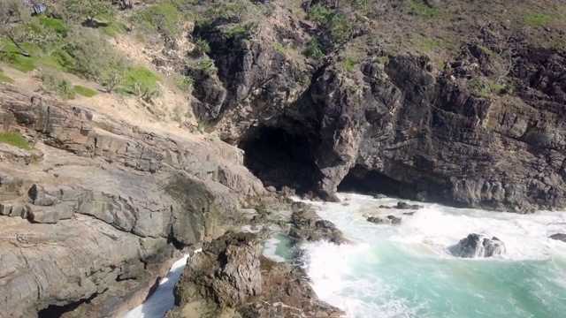 空中向前:岩石海岸与波浪进入黑暗，岩石洞穴，努萨，澳大利亚视频素材