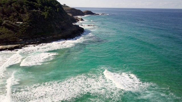 空中出口:蓝色海浪撞击岩石海岸的草崖，皇家国家公园，澳大利亚视频素材