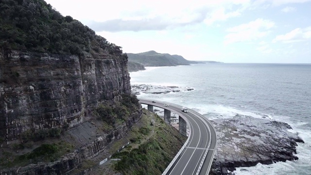 空中向前:海浪撞击岩石海岸的桥下悬崖，伍伦贡，澳大利亚视频素材