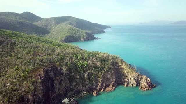 空中向前:充满活力的蓝色海洋与森林覆盖的山脉边缘，圣灵群岛，澳大利亚视频素材