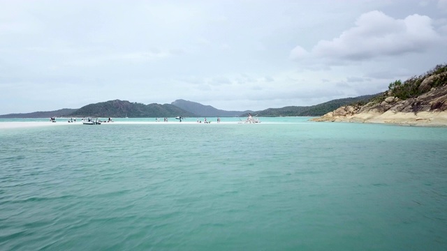 空中向前:一群人在浅蓝色的海洋上与树一起在沙地上放松，圣灵岛，澳大利亚视频素材