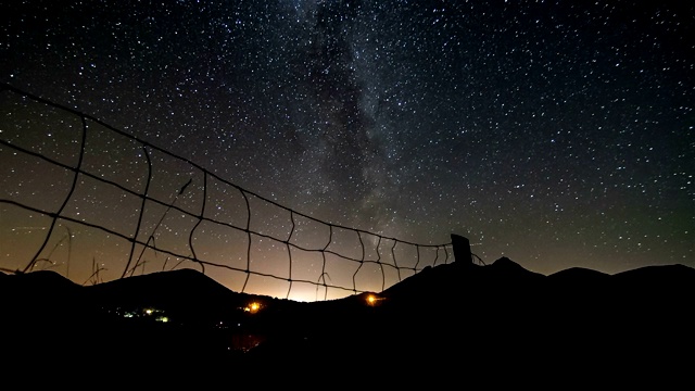 银河系的星星在繁星点点的夜晚越过乡村和栅栏，在夏季景观时间流逝天文学视频素材