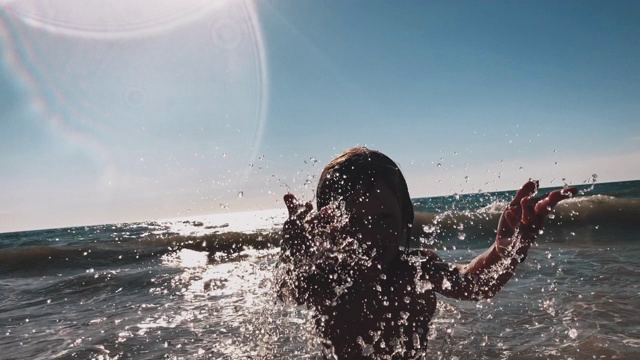 顽皮的男孩在海滩上溅起海水视频素材