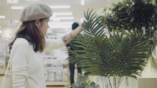 年轻女子在拿起花盆看和闻之前仔细看了一排沉溺的花视频素材