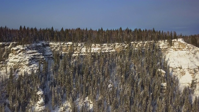 航拍:俄罗斯乌斯瓦的雪山，有岩壁和松林视频素材