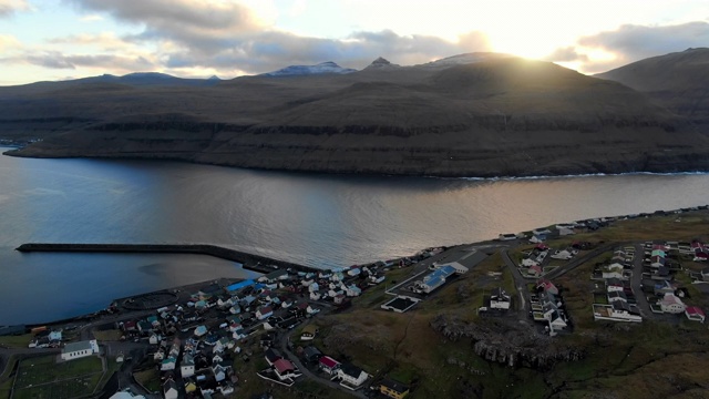 空中岩石山与村庄在湖的海岸，日落在美丽的山，斯特雷莫伊岛，法罗群岛的背景视频素材