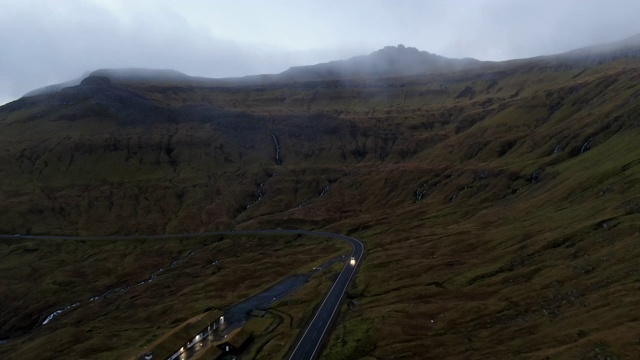 空中蜿蜒的道路穿过雾蒙蒙的青山，无人机向前移动，斯特雷莫伊岛，法罗群岛视频素材