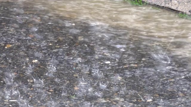 暴雨时，沥青路上满是水，雨点落在路面上视频素材