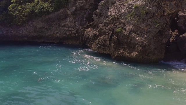 蓝色的海水和岩石峭壁景观。浪花溅起泡沫，溅向悬崖峭壁。绿松石海水和岩石岛。印尼巴厘岛视频素材