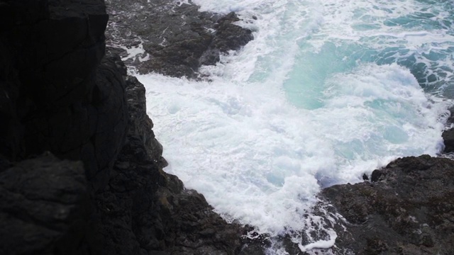 慢动作:海浪碰撞和白色的水上升对考艾岛火山岩，考艾岛，夏威夷视频素材