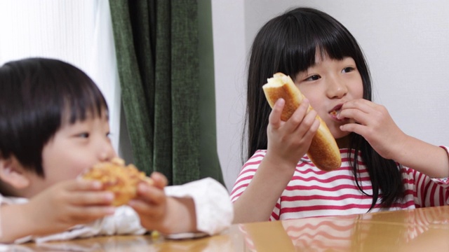 兄弟姐妹在吃面包。视频素材