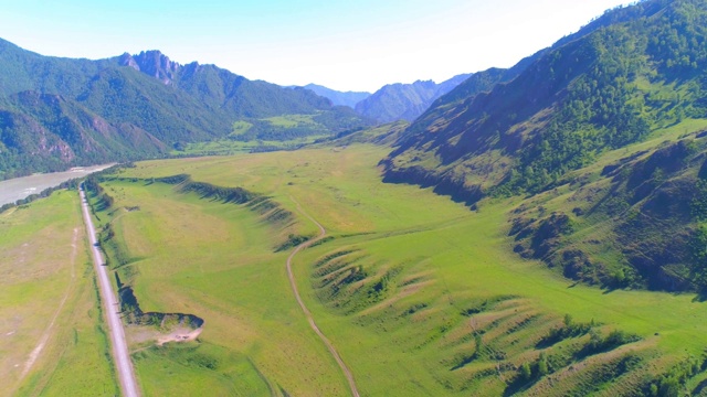 阳光明媚的夏日清晨，空中的乡村山路和草地。沥青公路和河流视频素材